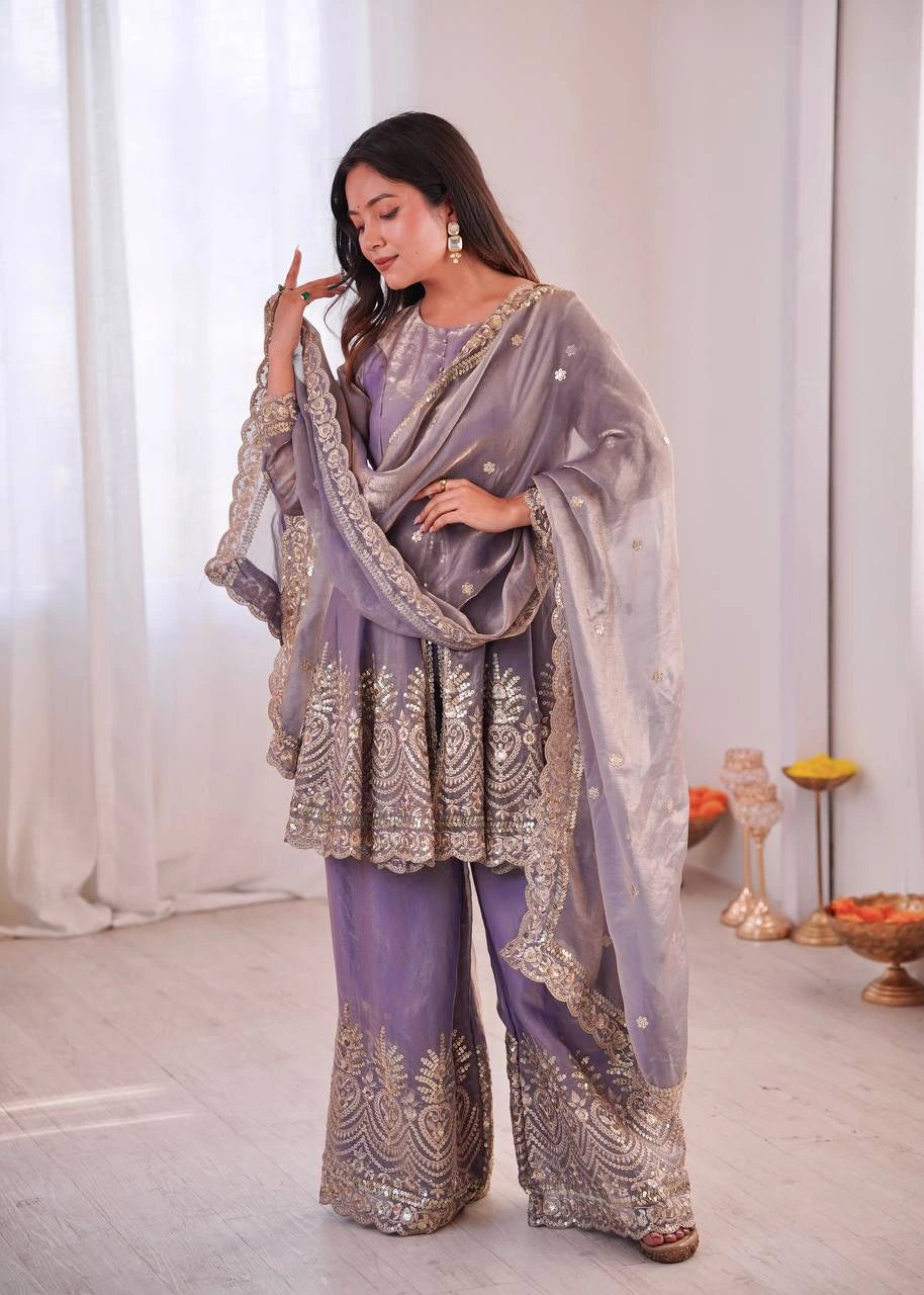 Woman in a lavender traditional outfit with intricate patterns indoors.