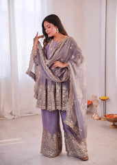 Woman in a lavender traditional outfit with intricate patterns indoors.