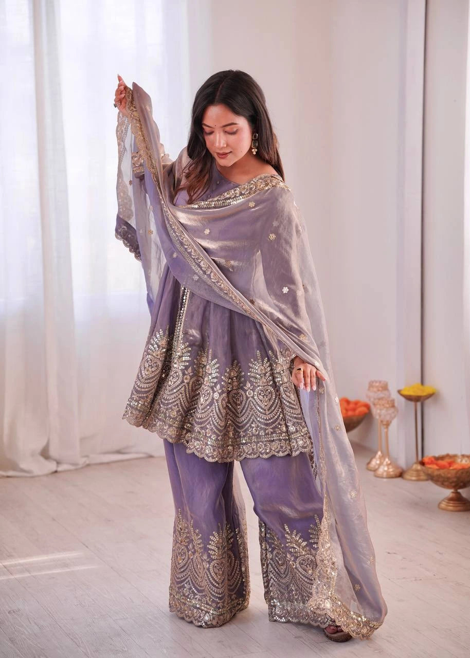 Woman in a lavender traditional outfit with intricate patterns, holding a dupatta.