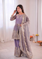 Woman in a lavender traditional outfit with intricate silver embroidery in a bright room.