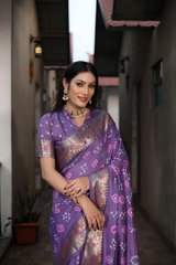 Woman in a purple saree with floral patterns standing in an alleyway.