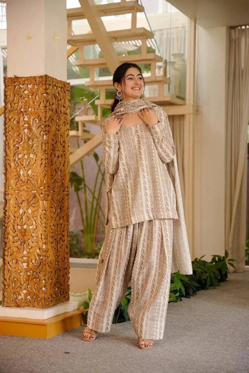 Woman in traditional attire standing in a decorative indoor setting with a wooden column and plants.