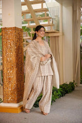 Woman in traditional outfit standing next to a decorative column indoors
