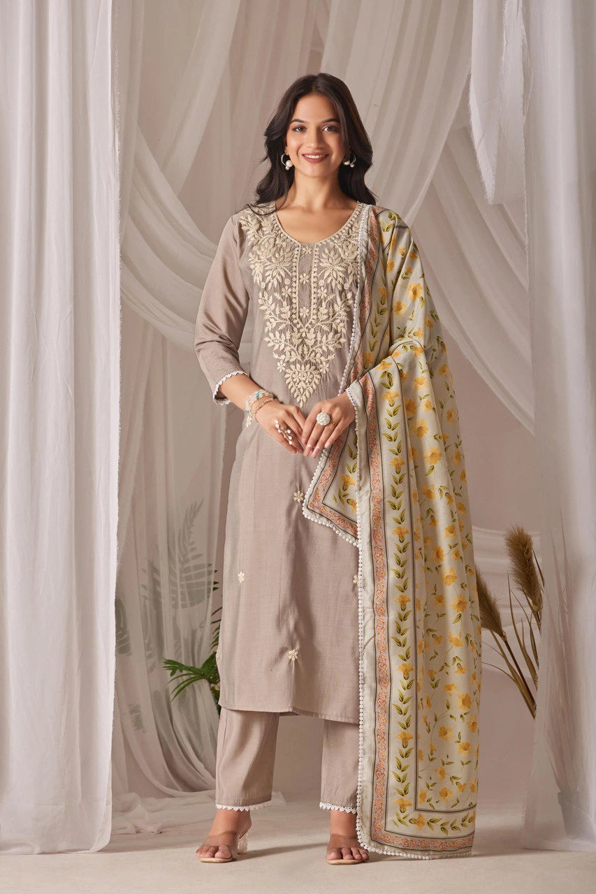Woman wearing a traditional outfit with a floral dupatta against a white curtain background