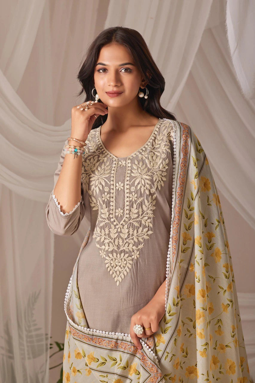 Woman wearing a traditional embroidered outfit with a floral shawl against a neutral background