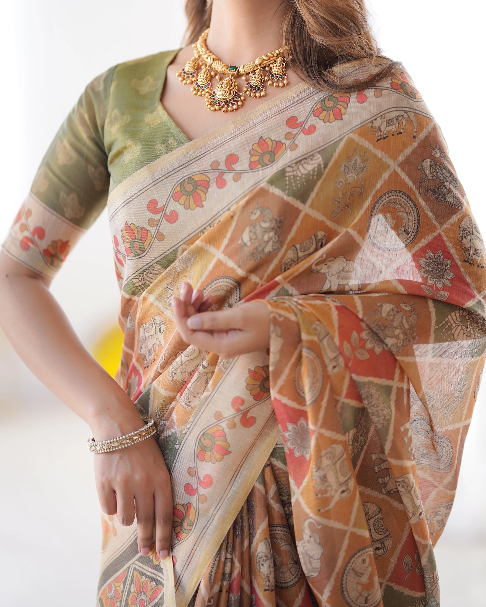Woman wearing a patterned saree with a gold necklace on a white background
