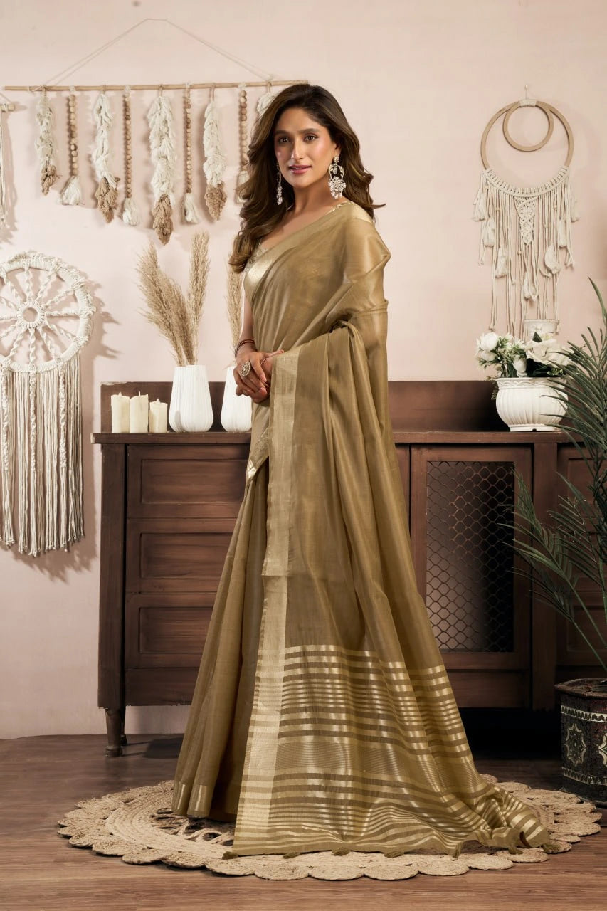 Woman in a green saree standing in a decorated room with plants and decor.