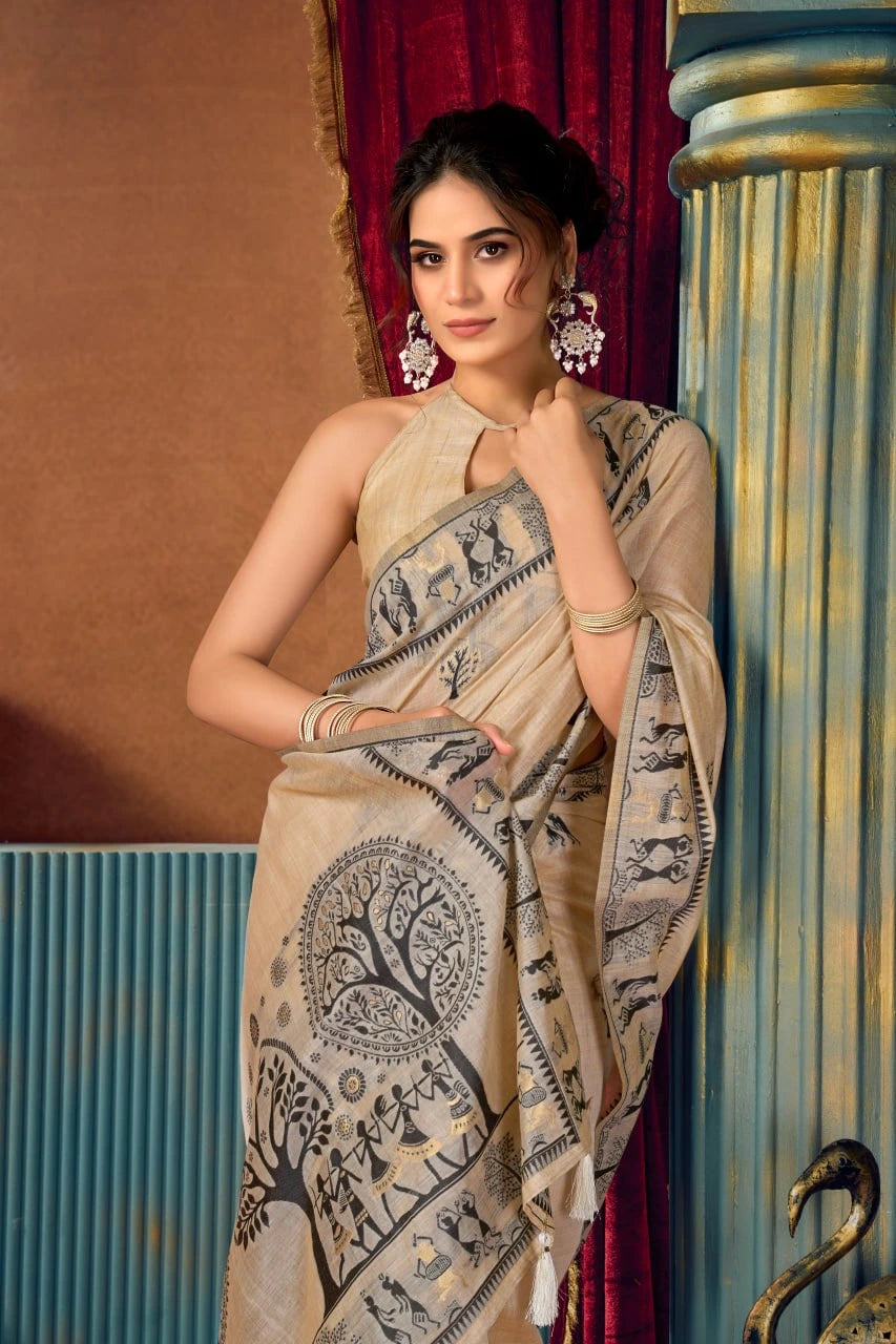 Woman wearing a beige saree with black patterns in an indoor setting