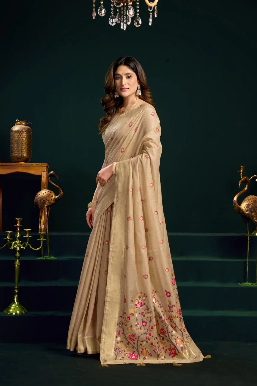 Woman wearing a beige saree with floral patterns in a dark setting