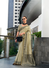 Woman in a saree standing in an urban setting with modern architecture.