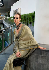 Woman in a light green traditional outfit with sunglasses and a black handbag on a balcony.
