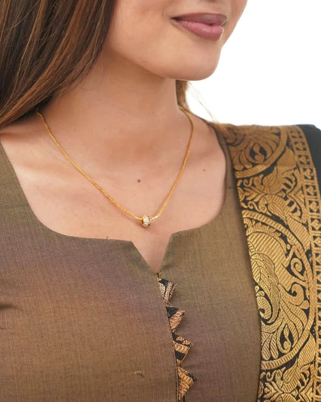 Woman wearing a gold necklace with a brown and black traditional outfit