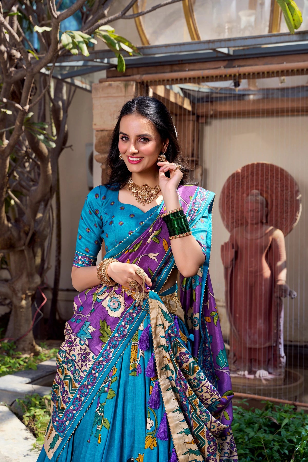 Elegant sky blue Kalamkari printed saree with purple floral pallu and artistic traditional border.