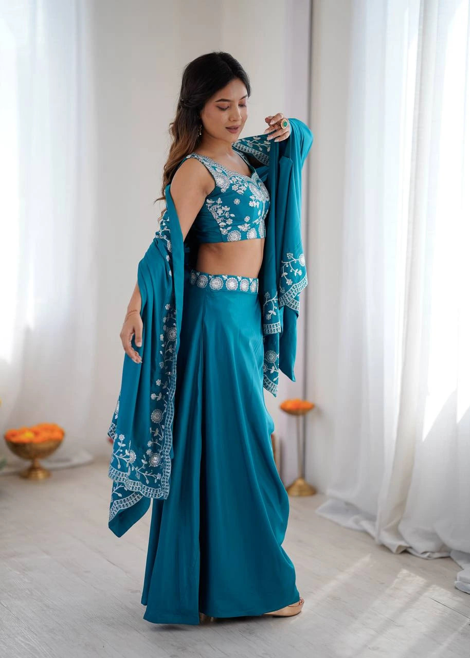 Woman in a teal traditional outfit with matching dupatta against a white curtain background