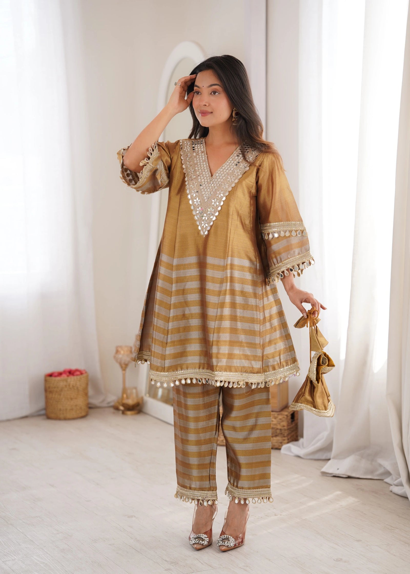 Woman wearing a gold and beige traditional outfit in a bright room.