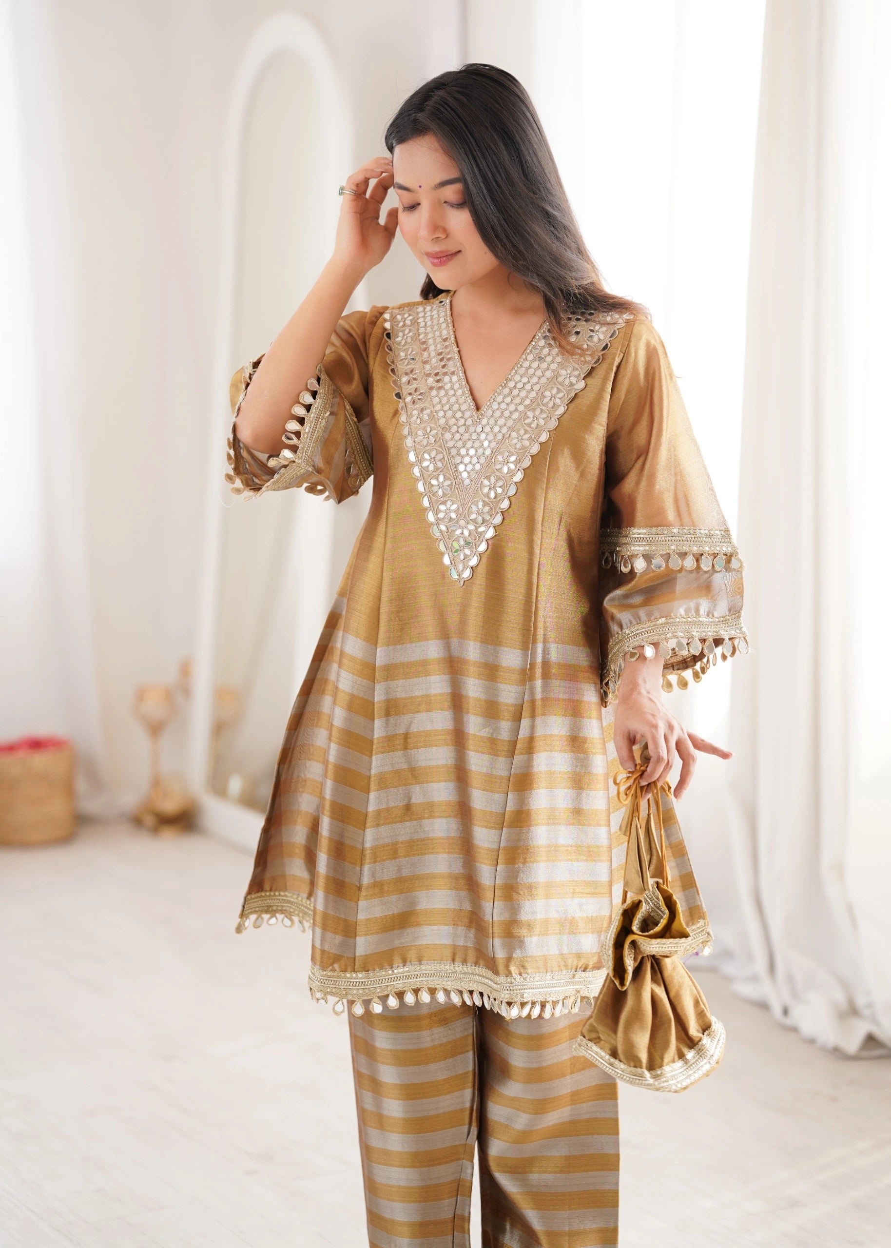 Woman wearing a gold and white traditional outfit with intricate designs.