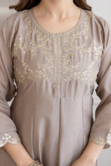 Brown dress with gold embroidery on a neutral background