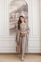 Woman in a gray traditional outfit standing in a room with decorative wall art.