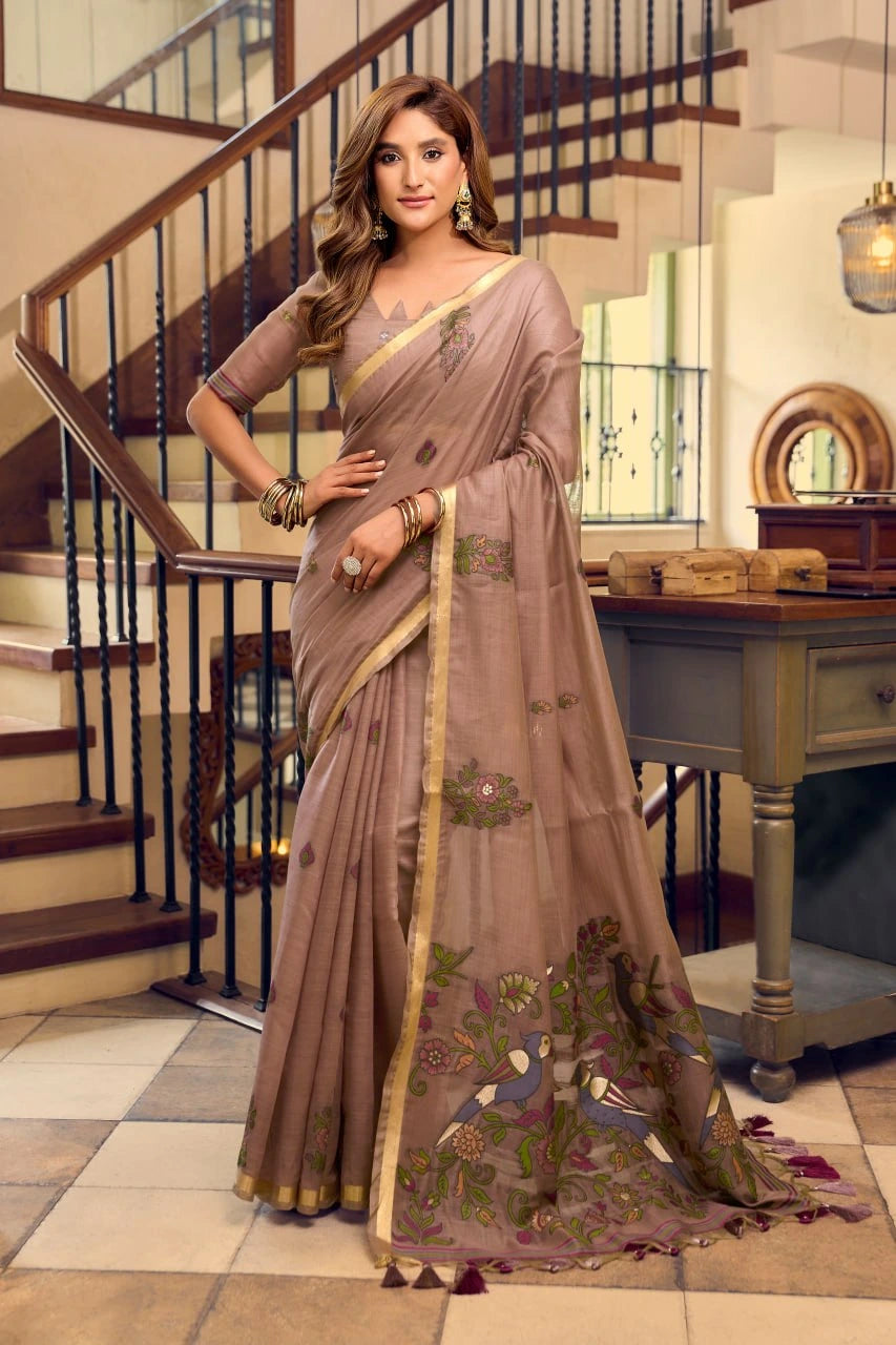 Woman wearing a brown saree with a floral pattern in an indoor setting.