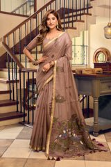 Woman wearing a brown saree with a floral pattern in an indoor setting.