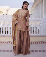 Woman in a traditional brown and gold outfit standing on a balcony.
