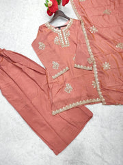 Peach-colored traditional outfit with intricate embroidery on a light gray background