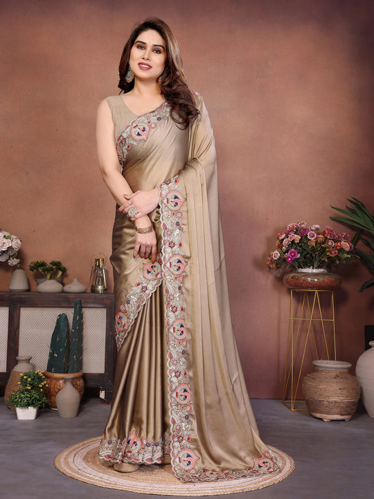 Woman wearing a beige saree with floral patterns in a decorated room.