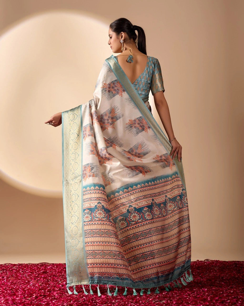 Woman wearing a traditional saree with a patterned design on a plain background