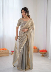 Woman wearing a saree in a minimalistic setting with decorative elements.