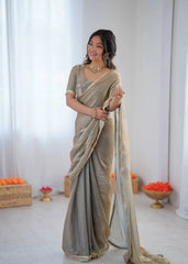 Woman wearing a saree with a neutral color palette in a minimalistic setting.