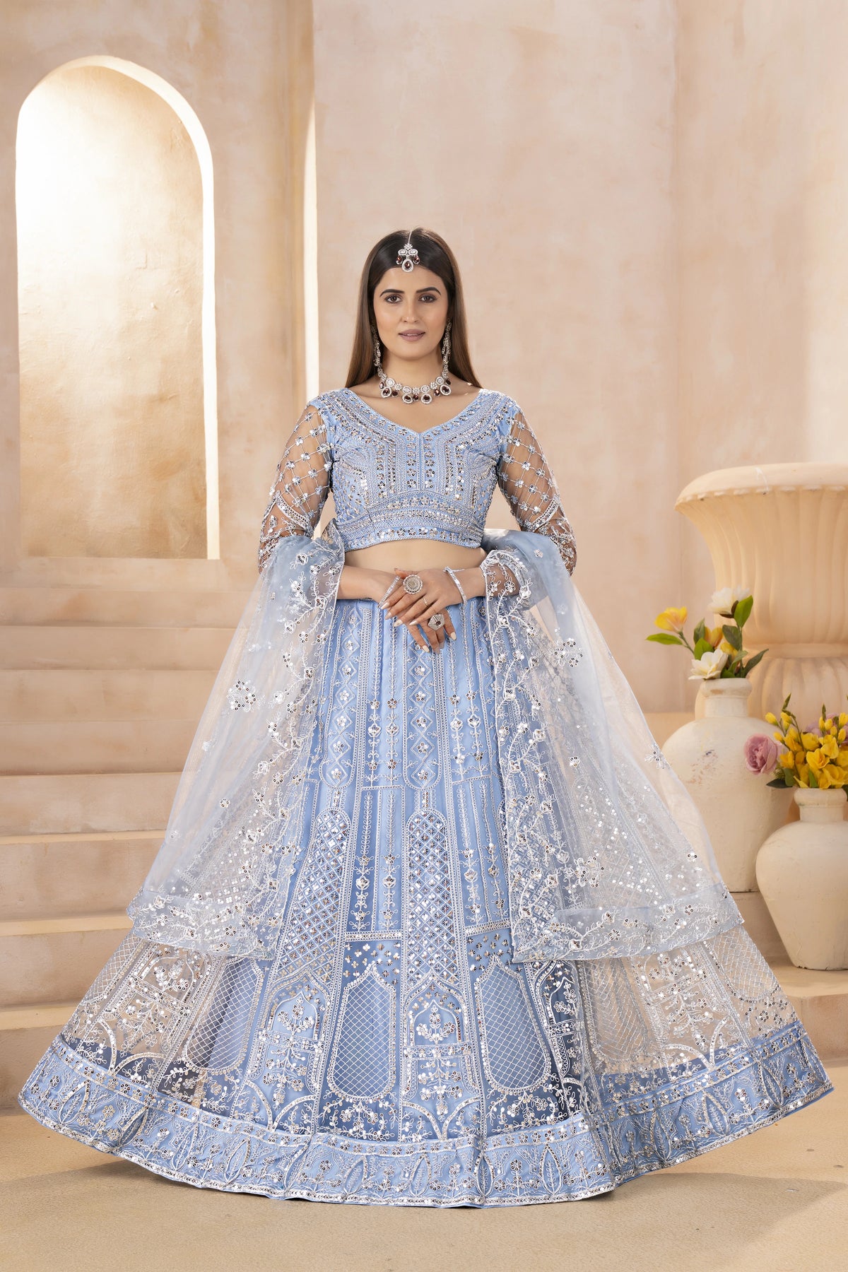 Woman wearing a light blue embroidered traditional outfit with a beige background