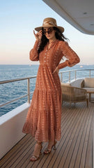Woman in a long orange dress and hat on a yacht deck with ocean view