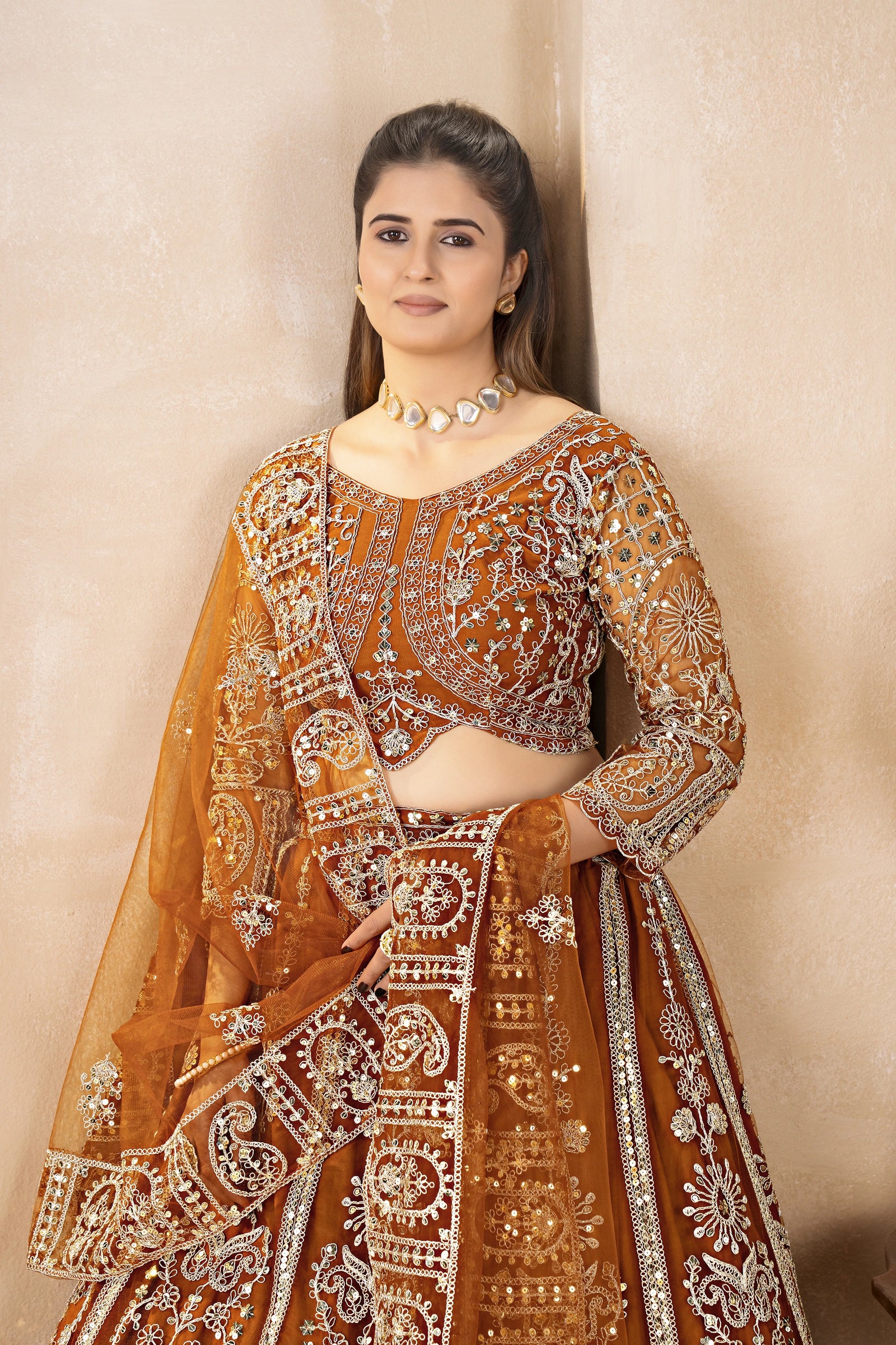 Woman wearing an ornate traditional outfit with intricate designs against a beige background