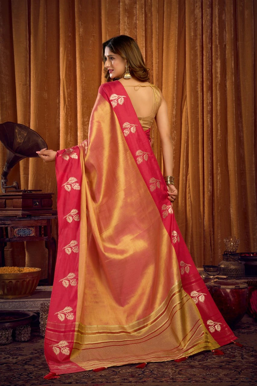 Woman wearing a pink and gold saree with a traditional setting in the background