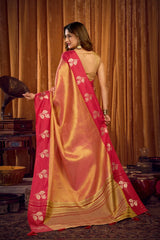 Woman wearing a pink and gold saree with a traditional setting in the background