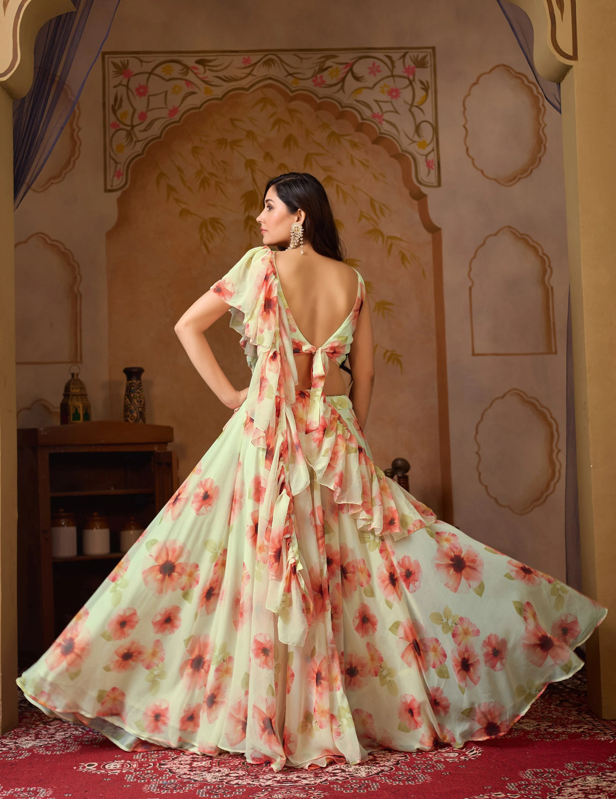 Woman in a floral dress standing in a decorated room with an archway.