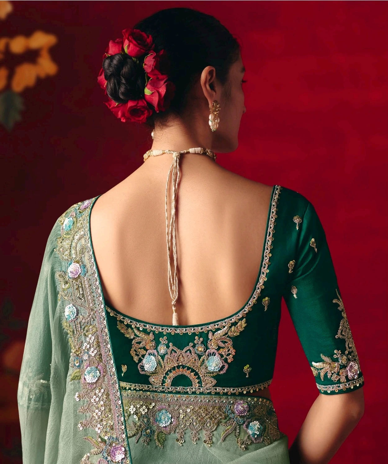 Woman wearing a green embroidered blouse with a red background