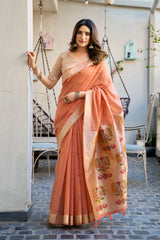 Woman in a peach saree with floral patterns standing outdoors.