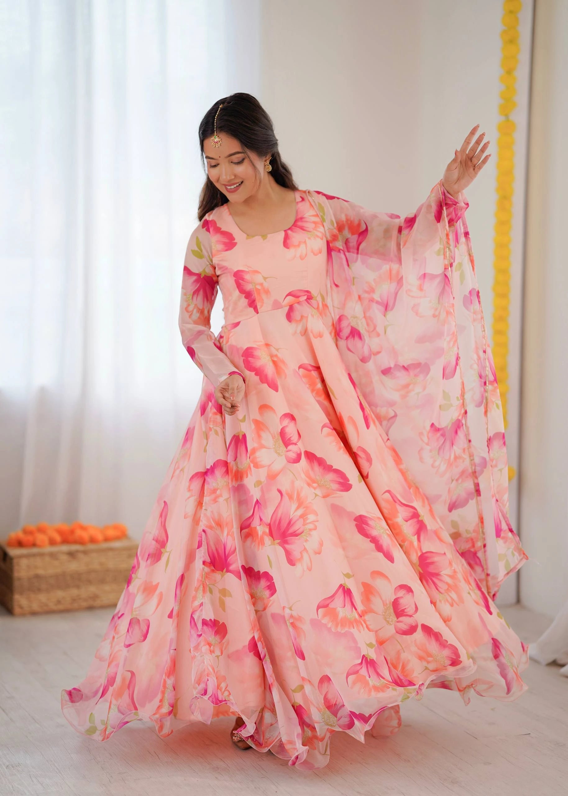 Woman wearing a pink floral dress in a bright room