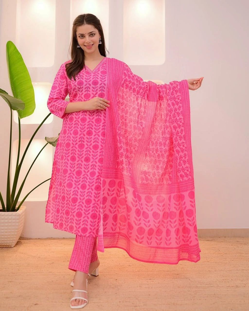 Woman wearing a pink traditional outfit with a matching dupatta in a well-lit room.