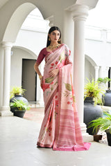 Woman wearing a pink saree with floral patterns in an elegant indoor setting.