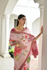 Woman wearing a pink floral saree in an outdoor setting with white columns.
