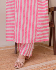 Person wearing a pink and white striped outfit sitting on a wooden chair.
