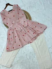 Pink and white striped dress with red heart patterns on a textured surface