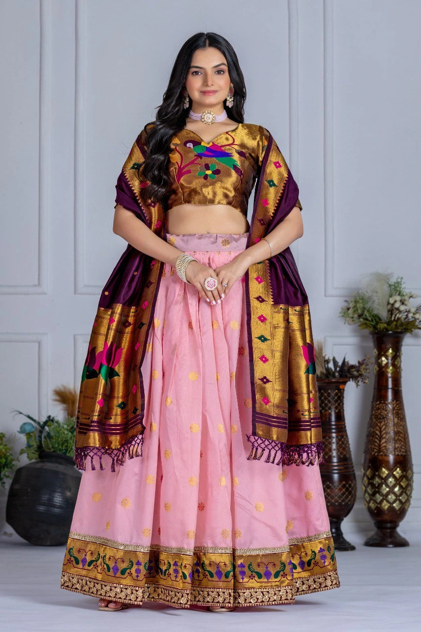Woman wearing a traditional outfit with a pink skirt and gold blouse against a white wall.