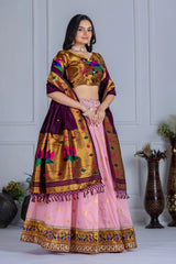 Woman wearing a traditional outfit with a gold and pink design against a white wall.