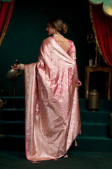 Woman in a pink saree standing in a dimly lit room with red curtains.