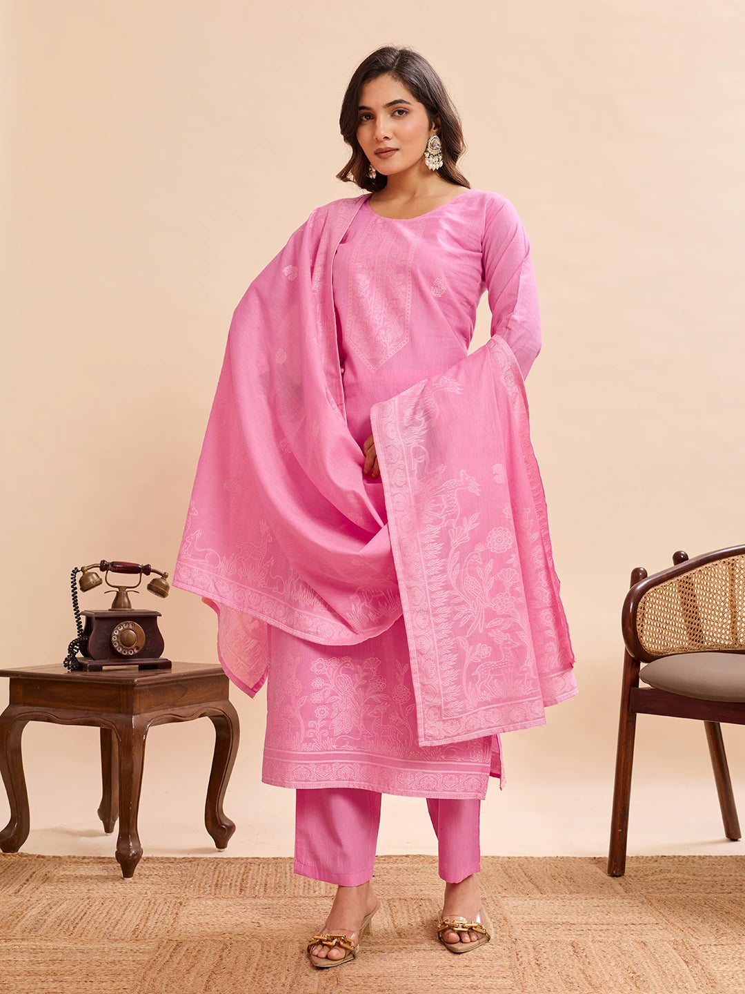 Woman wearing a pink traditional outfit with a scarf against a beige background