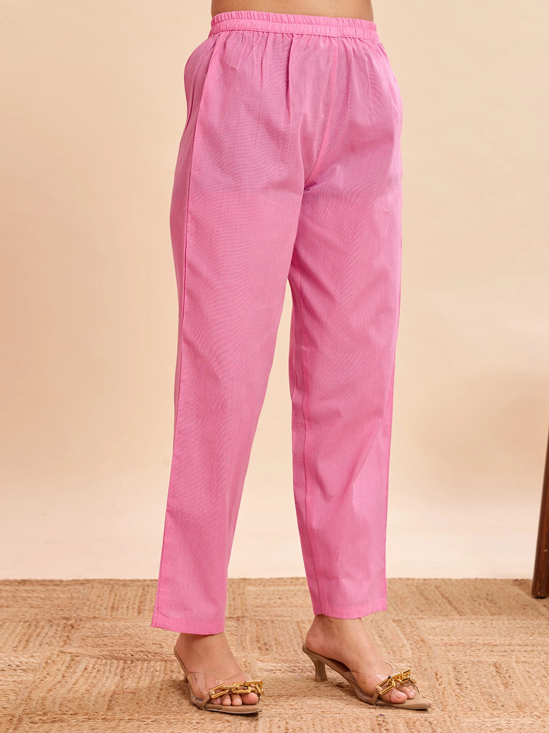 Pink pants worn by a person on a beige background