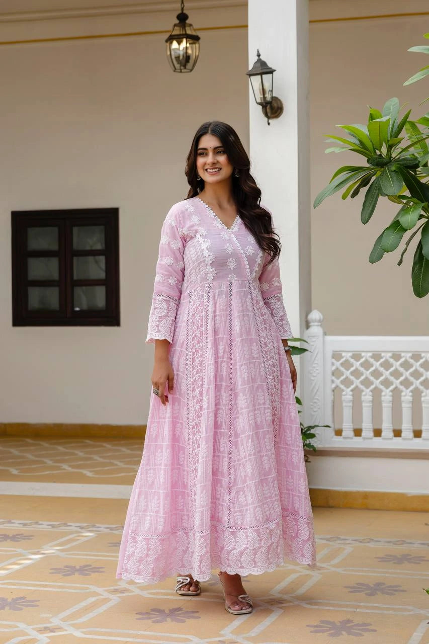 Woman in a pink dress standing in a decorative indoor setting with plants and architectural elements.